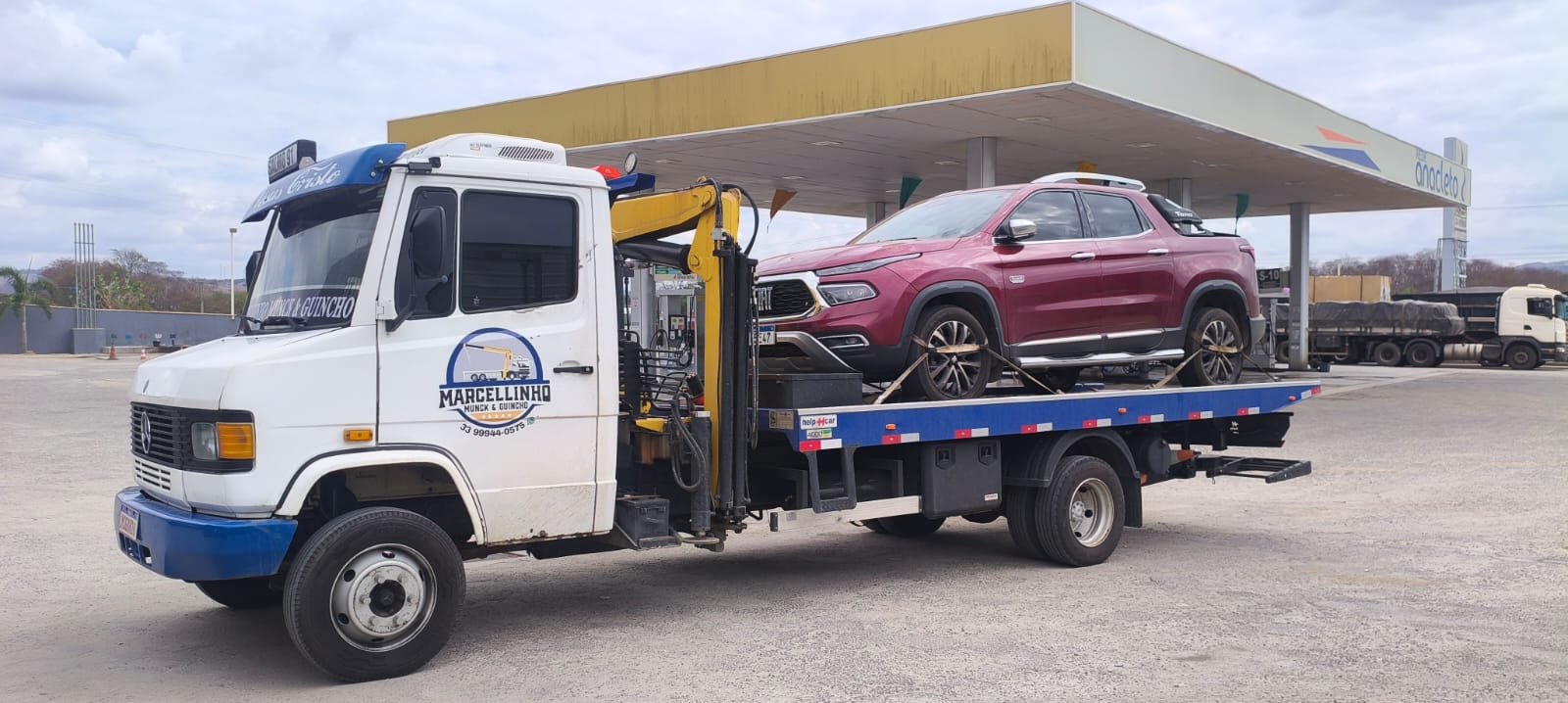 Picape Fiat Toro vinho presa com cintas na plataforma, em um posto.