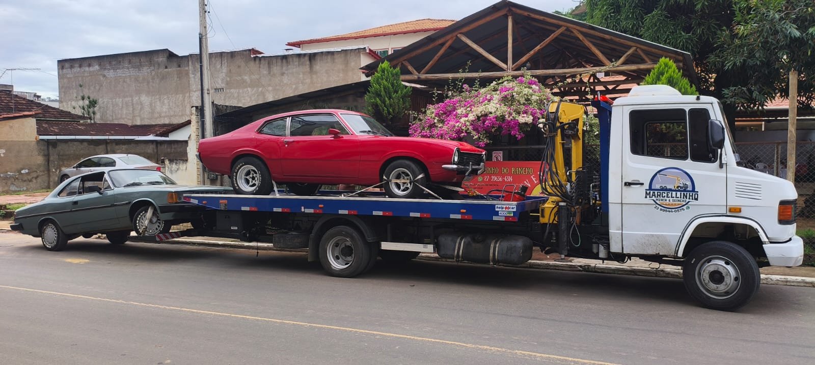 Ford Maverick vermelho na plataforma e um Opala engatado atrás.